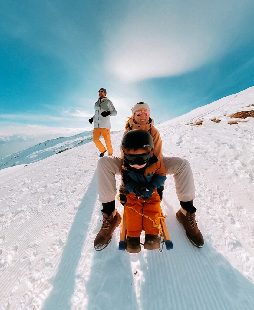 gezin is aan het sleeën in de besneeuwde bergen van flims laax in zwitserland